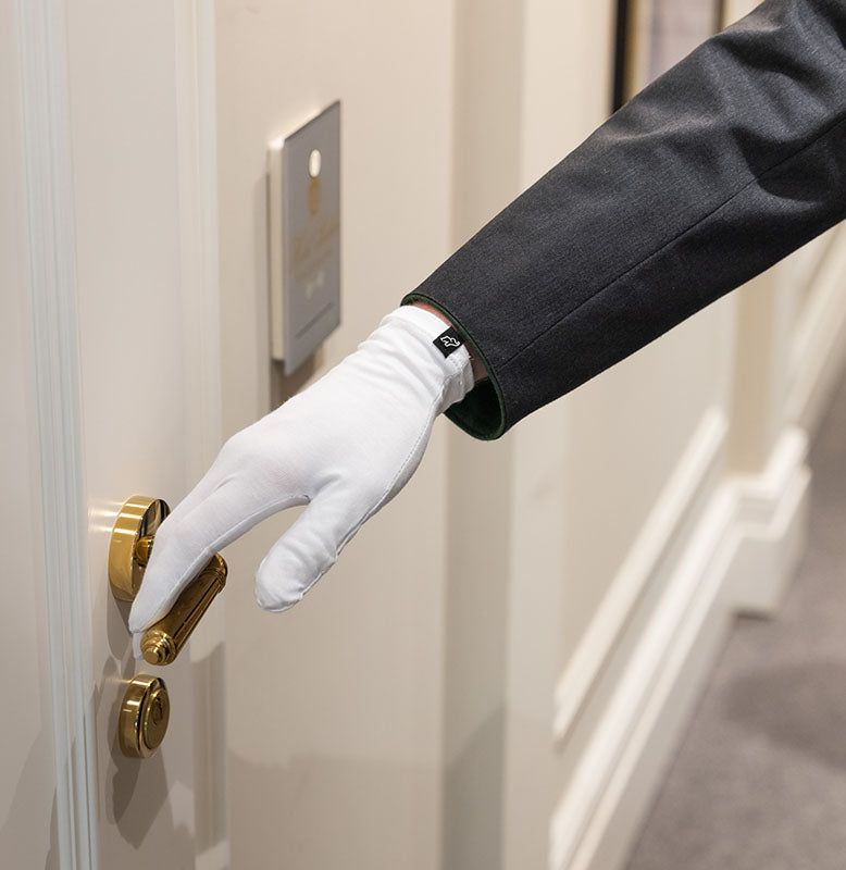 Hotelangestellter fasst Türklinke mit ElephantSkin Handschuhen an